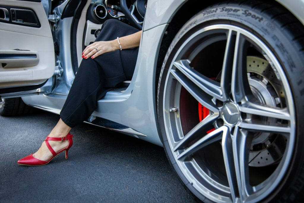 person in black pants sitting on white car