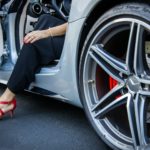 person in black pants sitting on white car