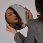woman in gray long sleeve shirt holding her head